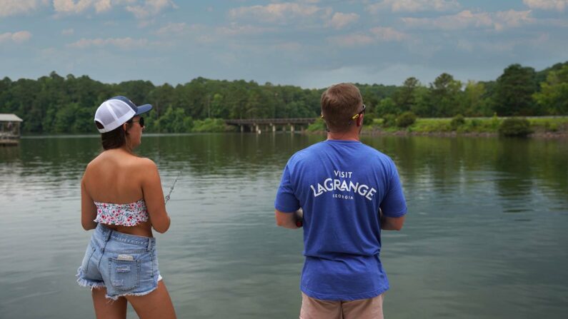 Two people fishing on West Point Lake, wearing Visit LaGrange merch.